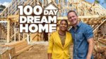 A couple stands in front of a framed out home under construction