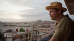 Actor Rainn Wilson looking over a balcony at a distant city.