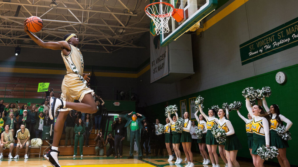 A teenage Lebron James leaping to a high school basketball hoop
