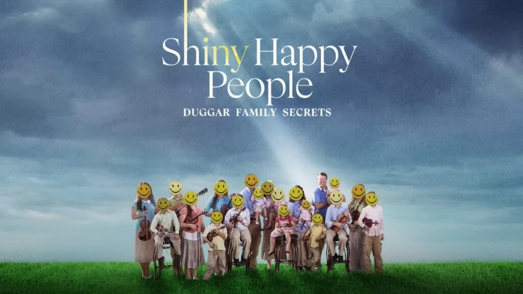 A very large family with many children in a sunny field with yellow smiley faces over their faces.