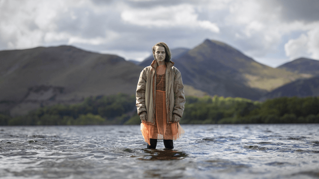 Neve Kelly standing in lake with mountains in background.