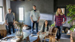 Four hip designers pose in a modern living room.