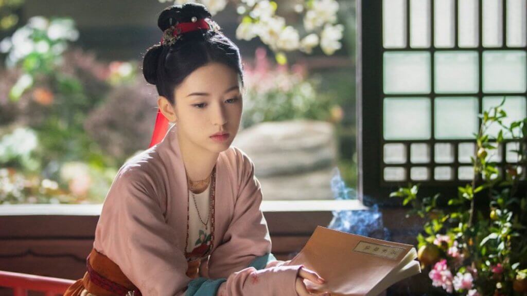 A young Chinese woman sitting in a traditional home holding a book