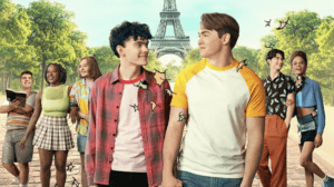 A group of teens with two boys holding hands in the center in front of the Eiffel tower.