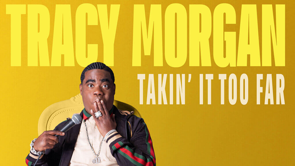 Comedian Tracy Morgan holding a microphone and making an "oops" face.