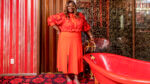 Actor and comedian Retta in a red outfit in an ugly red bathroom